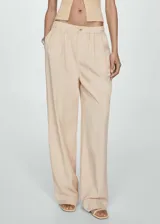 Pantalon de corte wideleg color beige, con cintura elástica, cierre frontal de cremallera y botón, y detalle de pliegues frontales.