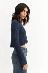 Sweater azul marino de punto trenzado, corte crop y mangas largas.