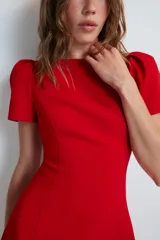 Vestido mono corto de color rojo, con cuello redondo y mangas cortas abullonadas. Cuenta con forro interior tipo shorts combinado a tono y cierre en la espalda con cremallera oculta.
