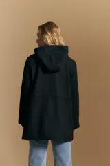 Tapado de paño color marrón oscuro con capucha, cierre frontal oculto con broches, bolsillos aplicados y ajuste interno en la cintura.