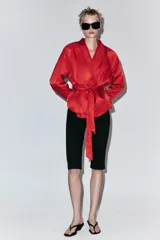Cazadora corta de Zara color rojo, con cuello smoking, manga larga y cinturón ajustable del mismo tejido.