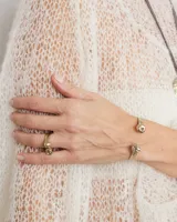 Brazalete rígido abierto de metal color plateado, con terminaciones en forma de herradura.