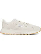 Championes Under Armour Street Mirage color beige, con parte superior de malla transpirable y superposiciones de gamuza. Cuenta con entresuela de EVA acolchada, suela exterior de goma con tracción y una etiqueta pequeña con el logo de la marca en el lateral.
