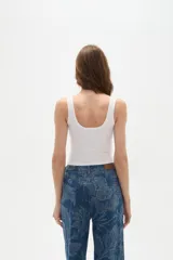 Musculosa blanca de bretel ancho con cuello profundo y cierre frontal con broches.