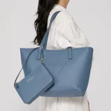 Cartera shopper de poliuretano color azul, con doble asa superior, diseño texturizado, gran compartimento principal y logo de la marca en relieve en la parte frontal. Incluye un pequeño bolso de mano tipo pouch con correa corta.