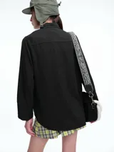 Camisa de corte oversize color bordó, con cuello clásico, cierre frontal de botones y mangas largas amplias con puños anchos. Presenta un diseño de caída fluida con bajo redondeado y levemente más largo en la parte posterior.