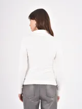 Polera de tejido de punto fino, con cuello alto doblado y mangas largas. Presenta un diseño ajustado al cuerpo con terminaciones acanaladas en puños y ruedo.