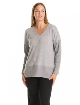 Buzo de calce suelto confeccionado en tejido melange de punto suave, con escote en V, mangas largas con hombros caídos y detalles de tejido rib en puños y ruedo. Presenta aberturas laterales y un diseño asimétrico con la parte posterior ligeramente más larga.