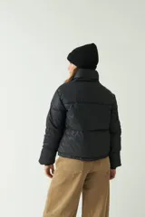 Campera puffer negra con cuello alto y cierre frontal con botones a presión.