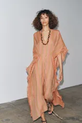 Vestido largo tipo kaftán confeccionado en lino a rayas verticales en tonos naranja y verde. Tiene cuello redondo con escote en V, mangas cortas amplias, acabado deshilachado y cinturón de cordón en el mismo tejido.