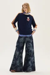 Sweater de tejido de punto azul marino con mangas raglan en color camel y puños con detalles en rojo y beige. Presenta un aplique bordado en el pecho con motivos de fantasía.