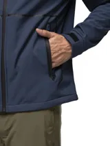 Campera softshell negra con capucha ajustable, cierre frontal completo y bolsillos laterales con cierre. Presenta puños con ajuste de velcro y logo de la marca estampado en el pecho.