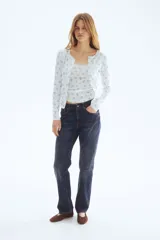 Cardigan ajustado de punto pointelle en color blanco, con pequeño estampado floral azul, escote redondo y cierre frontal de botones con ribetes de picot.