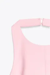 Top rosa claro, entallado, con cuello halter que se abrocha en la nuca y espalda descubierta. El bajo tiene un corte peplum acampanado.
