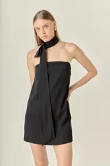 Vestido corto negro sin mangas con cuello choker y corbatín.