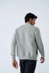 Campera tejida de algodón en color bordó, con cierre frontal completo, cuello alto y logo bordado en el pecho.