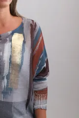 Sweter de punto con diseño abstracto en tonos terracota, azul petróleo, gris y blanco, con detalles de pinceladas doradas brillantes en el frente. Presenta cuello redondo, mangas tres cuartos y un corte holgado.