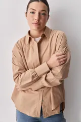 Camisa celeste de corte oversize, con mangas largas, cuello camisero y cierre frontal de botones.
