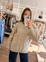 Sweater de tejido de punto grueso con diseño de trenzas en relieve, cuello redondo, mangas largas y terminaciones acanaladas en puños, cuello y cintura.