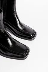 Botín de cuero con estampado de piel de serpiente en tonos blanco y negro, con puntera cuadrada y tacón bloque bajo.