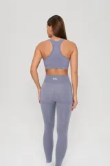 Conjunto deportivo de tres piezas en color lavanda, compuesto por un top de manga larga con orificios para pulgares, un top de bretel ancho y una calza chupín de tiro alto. La prenda presenta un diseño seamless con detalles de texturas perforadas estratégicamente ubicadas para mayor ventilación.