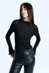 Remera de algodón con textura acanalada, corte ajustado al cuerpo, cuello redondo y mangas largas con terminación acampanada. Incluye detalle de chapita metálica en forma de corazón.