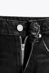 Shorts de denim azul claro, tiro medio, con cinco bolsillos y roturas grandes y deshilachadas en la parte delantera. El bajo es deshilachado.