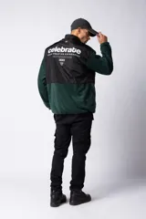 Campera de polar con recortes en tela técnica tipo sire en la parte superior frontal. Presenta cierre frontal completo, cuello alto y bolsillos funcionales en el pecho. Diseño bicolor en tonos verde oliva y negro con logo de la marca en el pecho.