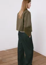 Chaqueta verde militar corta con cuello camisero de pana marrón oscuro, cierre frontal de botones, bolsillos aplicados en el pecho y diseño holgado.