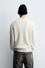 Jersey de punto con textura efecto pelo, corte boxy fit, cuello redondo y manga larga con acabados en rib.
