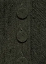 Buzo de punto fino color verde oscuro, con cuello perkins y manga larga. Presenta un diseño semitransparente con abertura lateral y cierre de botones decorativos en el costado.