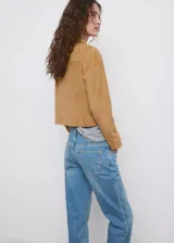 Chaqueta corta de piel caprina en color tostado, con cuello camisero, cierre frontal de botones y bolsillos de parche con solapa en el pecho.
