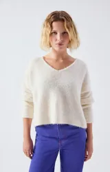 Sweater de punto fino en color beige, con escote en V, mangas largas y corte holgado.