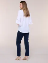 Blusa blanca de crepe crinkle con escote en V, media abotonadura frontal con botones nacarados, alforzas verticales en la pechera y mangas tres cuartos acampanadas con detalle de encaje horizontal.