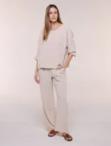 Pantalón pull-on de color beige con caída fluida, cintura elastizada fruncida, bolsillos laterales funcionales y pierna amplia de corte wide leg.