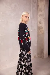 Sweater de lana tejido y bordado a mano, de color negro con diseño de figuras humanas coloridas en el frente y mangas. Presenta un calce holgado, cuello a la base y puños acanalados.