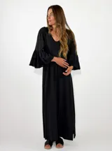Vestido largo negro de corte holgado, con escote en V y mangas largas con volados en los puños.