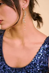 Aros colgantes largos dorados con diseño ondulado pavé de circonias y detalles de pedrería transparente.