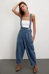 Jardinero de denim azul con silueta holgada tipo balloon, tirantes ajustables, bolsillos delanteros de parche y botones laterales.