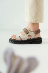 Sandalias de cuero con diseño tipo fisherman, en combinación de colores beige y marrón. Presentan una suela track negra de goma con plataforma y cierre mediante tiras de velcro ajustables.