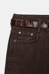 Jeans de tiro alto color azul oscuro, con cinco bolsillos, pernera ancha y nervio marcado en el delantero. Incluye un cinturón fino de cuero sintético marrón con textura de cocodrilo. Cierre frontal con cremallera y botón.