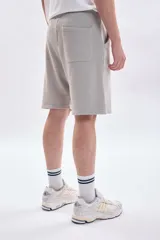 Bermuda de corte recto con efecto lavado en color gris claro, confeccionada en tejido de algodón con cintura elástica y cordón ajustable.