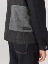 Campera de diseño híbrido con frente acolchado en color tostado, solapas y cuello en tejido de lana con patrón de cuadros tipo príncipe de gales, y mangas en paño de lana color azul marino. Cuenta con cierre frontal de botones.
