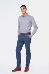 Pantalón de gabardina color marrón claro, corte slim fit, con bolsillos laterales y traseros. Se ajusta a la cintura con cinturón de cuero marrón.