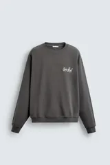 Sudadera gris oscuro de corte relaxed fit, cuello redondo y manga larga, con estampa en contraste en el pecho y acabados en rib.