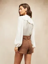 Short de gamuza color marrón, con diseño de tiro alto, pinzas frontales y bolsillos laterales.