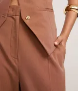 Pantalón de vestir color marrón, de corte recto y tiro alto, con cierre frontal y bolsillos delanteros.