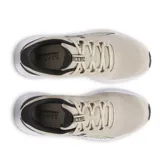 Championes de running Under Armour modelo Charged Surge 4, color beige con detalles en negro y suela blanca. Confeccionados en malla transpirable con refuerzos sintéticos laterales para mayor soporte y entresuela con tecnología Charged Cushioning para una amortiguación reactiva.