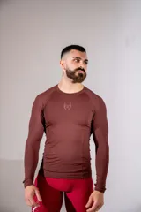 Remera de lycra de manga larga, corte ajustado, color marrón, con cuello redondo y logo bordado en el centro del pecho.