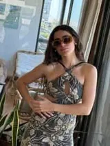 Vestido corto negro con estampado de plumas doradas, escote en V, breteles finos cruzados en la espalda, cut-outs laterales y volado en el ruedo.